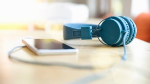 pair of blue over the ear headphones connected to an mp3 player sitting on a table